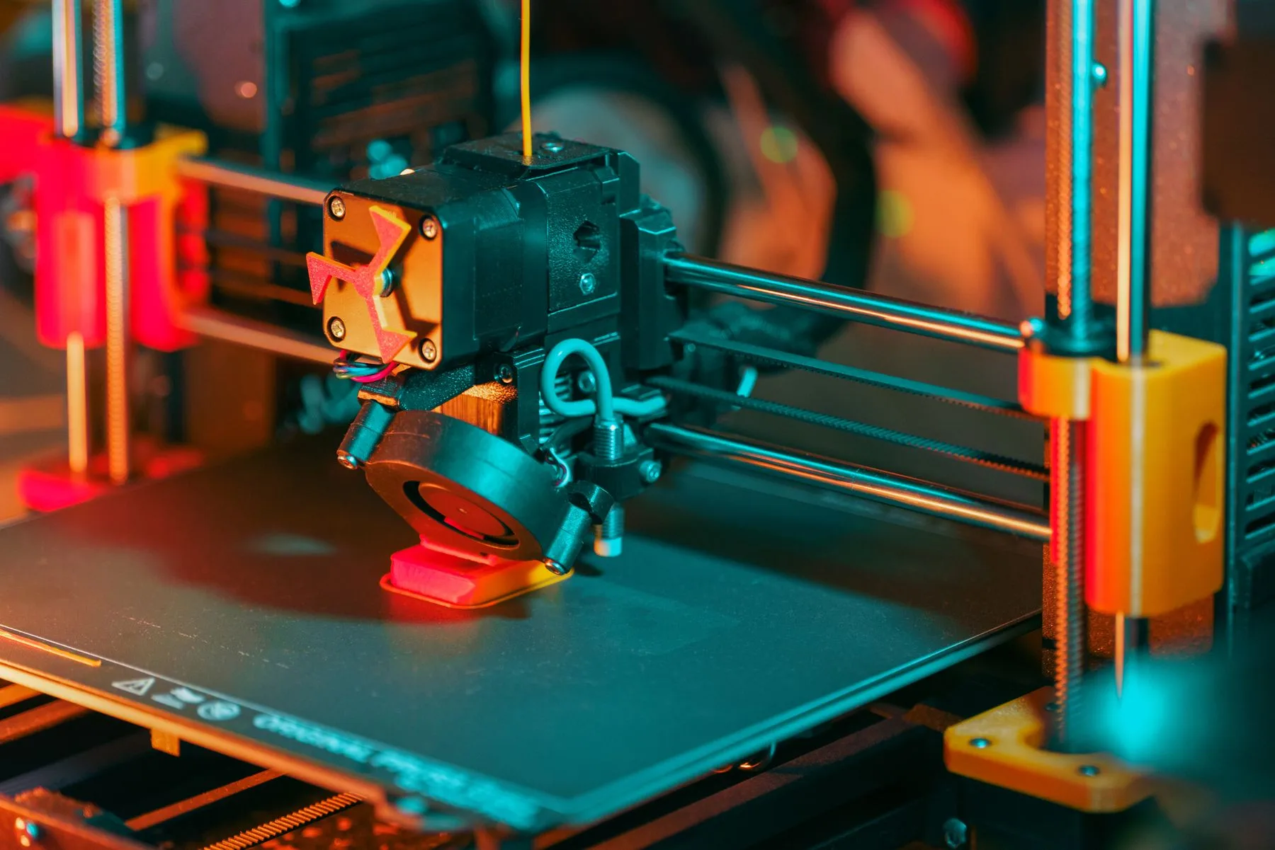 Close-up of an extrusion 3D printer building a component on the print bed.