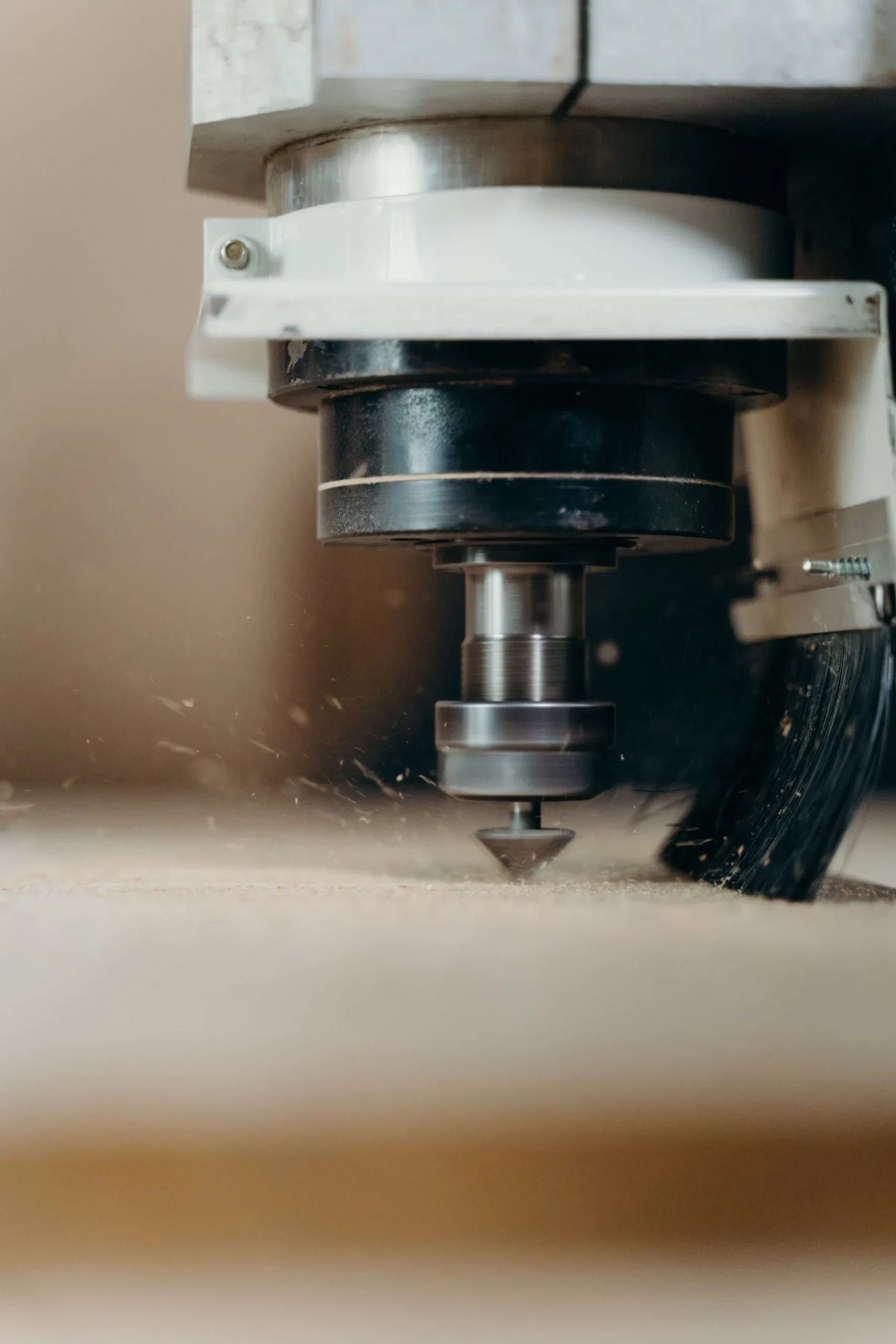 CNC router cutting a wood panel inside an enclosed machining area.