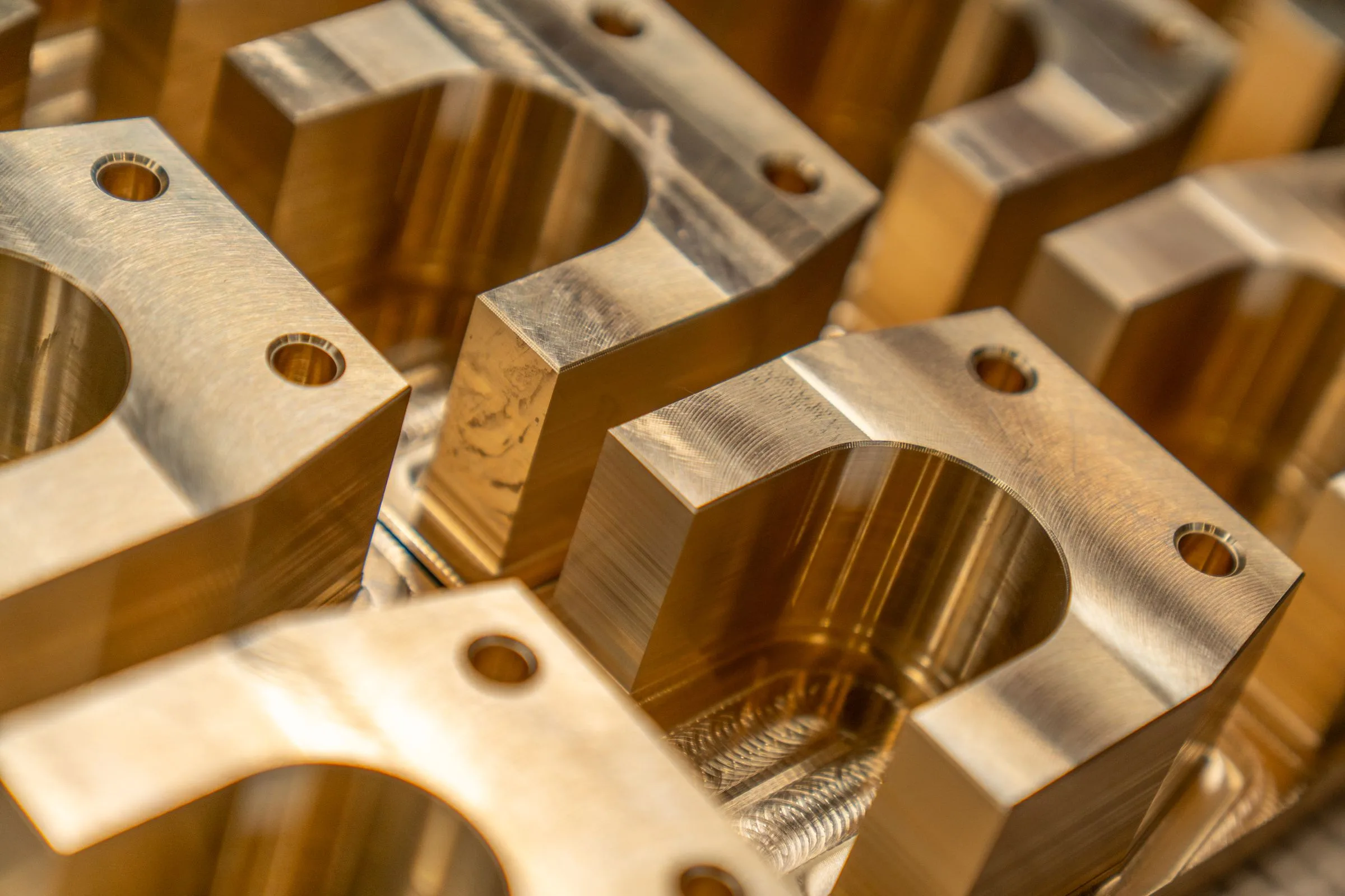 Close-up of precision-machined brass components with milled openings and drilled holes.